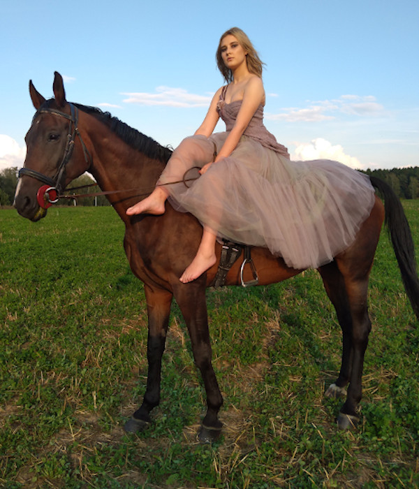 Фотография девушки верхом на тёмно-гнедой лошади.