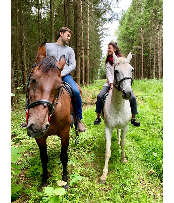 Фотография пары на лошадях в лесу.
